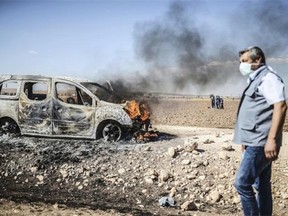 A man walks past a burning car as Kurdish protestors clashed with Turkish soldiers near the Syrian border after Turkish authorities temporarily closed the border at the southeastern town of Suruc in Sanliurfa province, on September 22, 2014. Turkey said on September 22 that some 130,000 people had flooded across its border from Syria as Kurdish fighters battled Islamic State group jihadists trying to capture a strategic town.