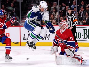 Vancouver Canucks' Daniel Sedin jumps to avoid the incoming puck in front of Canadiens goalie Carey Price during the NHL game at the Bell Centre on Feb. 6, 2014.