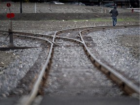 A man walks down the tracks in downtown of Lac-Megantic, Que Tuesday, June 10, 2014, where an oil-filled train screeched off the tracks and exploded a year ago killing 47 people.