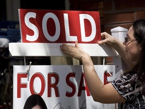 A real estate agent puts up a "sold" sign in front of a house in Toronto on April 20, 2010.