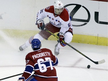 Washington Capitals' Andre Burakovsky, top, moves the puck on Montreal Canadiens' Max Pacioretty (67) during the first period of an NHL hockey game, Thursday, Oct 9, 2014, in Washington.