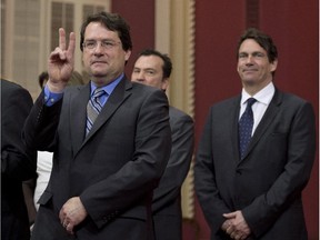 Opposition MNA Bernard Drainville gestures to applauds as PQ members are sworn in, Tuesday, April 22, 2014 at the legislature in Quebec City. MNA Pierre Karl Peladeau, right, looks on. A clash now is brewing between the two  - both of them PQ leadership contenders - over whether the Bloc Québécois remains relevant to Quebec politics.