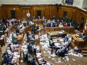 Montreal Mayor Denis Coderre, standing, speaks during a City Council meeting in a room littered with papers from an earlier protest by the firefighter's union at Montreal city hall in Montreal on Monday, Aug. 18, 2014.