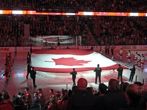 A giant flag was held at centre ice as a tribute to fallen soldier Nathan Cirillo before a game between the Flames and Carolina Hurricanes at Calgary's Scotiabank Saddledome on Oct. 23, 2014.