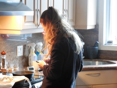 Cooking and staring at her cellphone - please do not burn the food.