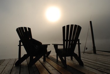 Sunrise on the dock: a boy momentarily forgets the Internet connected world we live in, and appreciates a simple moment, watching a late summer sunrise through the morning mist over Bark Lake.