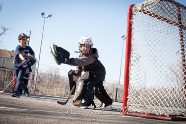 Enjoying the first of the warm sunny days to come, Ryan McJannet takes a shot on AJ D'Elia at Drummond Park in Beaconsfield during a ball hockey game after school.