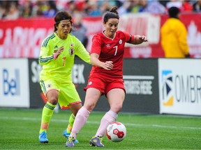 Canada's Rhian Wilkinson runs with the ball past Kozue Ando of Japan during a match at Edmonton's Commonwealth Stadium on Oct. 25, 2014. Japan won the game 3-0.