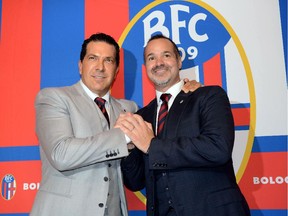 Joe Tacopina, right, and Joey Saputo pose in front of the Bologna Football Club logo in Bologna, Italy, on Oct. 16, 2014.