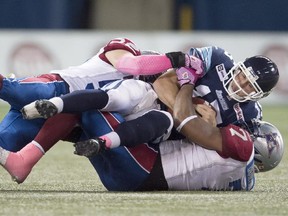 Argonauts quarterback Ricky Ray is sacked by  Alouettes defensive- end John Bowman (7) and linebacker Nicolas Boulay (52) during first half of CFL action in Toronto on  Oct. 18, 2014.