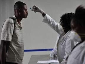 Kenyan health officials take passengers temperature as they arrive at the Jommo Kenyatta International Airport (JKIA) on August 14, 2014 in Nairobi. The World Health Organization classified Kenya as a high-risk area for transmission of the deadly Ebola virus yesterday, as Sierra Leone reported that a second leading physician has died of the disease. Eventhough there have been no reported cases of Ebola in Kenya, the countrys role as a transportation hub in East Africa makes it more vulnerable to the disease, WHO said.