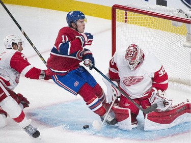 Montreal Canadiens' Brendan Gallagher, centre, slides in on Detroit Red Wings goaltender Jimmy Howard as Red Wing's Kyle Quincey, left, defends during second period NHL hockey action in Montreal, Tuesday, October 21, 2104.
