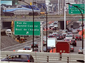 Traffic (including a commuter train) moves through and around the L'Acadie Circle area.