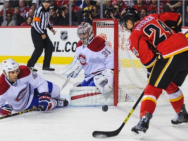 Jiri Hudler of the Calgary Flames takes a shot as Mike Weaver and Carey Price defend at Scotiabank Saddledome on Tuesday, Oct. 28, 2014, in Calgary.