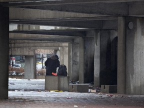 A man takes shelter from the rain at Viger Square, where many homeless people camp, in Montreal, Tuesday April 8, 2014.