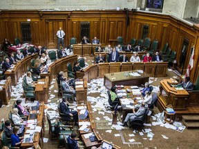 Montreal Mayor Denis Coderre, standing, speaks during a City Council meeting in a room littered with papers from an earlier protest at Montreal city hall in Montreal on Monday, August 18, 2014.