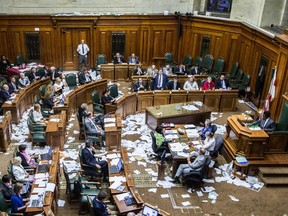 Montreal Mayor Denis Coderre, standing, addresses a city council meeting in a room littered with papers from an earlier protest by the firefighter's union at Montreal city hall in Montreal on Monday, August 18, 2014.  The firefighters were demonstrating at city hall against the proposed Bill 3, a pension reform bill.