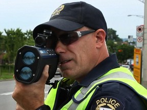 A Laval police officer points his radar gun at oncoming traffic.