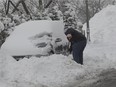 A man digs out his car with his shove on Summit road in Montreal on Tuesday, March 19, 2013.