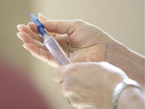 A nurse readies a needle.