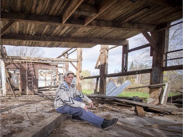 Roger Brabant of Rigaud relaxes inside a disassembled barn as he works to reclaim some of the wooden beams and planks Monday, October 27, 2014.