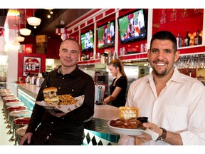 Jukebox Burgers owner Marc Emond, left, holds the The Tower Burger, which has 6 patties, 6 slices of cheese, 6 strips of bacon, mayo and lettuce while manager Elan Azran displays The Southern Comfort, which is comprised of Corn Flake-fried chicken, candied bacon, Monterry Jack cheese, maple mayo and it is served with two waffles acting as the bun, with a side of hot sauce.