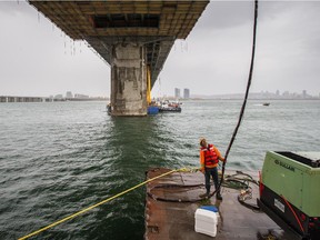 A construction worker stands on a floating service platform under the Champlain Bridge on Wednesday, Oct. 15, 2014.