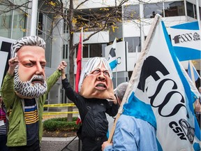 Protesters wearing masks of Quebec Premier Philippe Couillard, left, and Minister of Health Gaétan Barrette in Montreal last October denounce cuts to the health-care system.