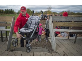Philippe Quinn helps a visitor place a child's stroller onto the trailer used to get visitors around Quinn's Farm in Ile-Perrot on Sunday, Oct. 19, 2014.