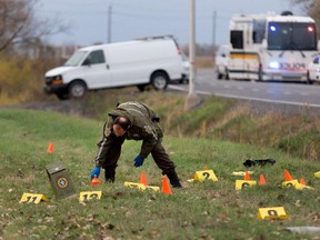 Sûreté du Québec investigators go over the scene of a police shooting in St. Jean-sur-Richelieu on Monday.  An evidence bag covers a knife the suspect is alleged to have been holding when he was shot dead by police.  A police officer identified the man as Martin Couture Rouleau, 25, a local resident.