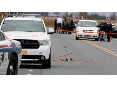 Sûreté du Québec police investigators go over the scene of a police shooting in Saint-Jean-sur-Richelieu near Montreal on Monday October 20, 2014.  A motorist ran over 2 soldiers and fled the scene, when confronted by police he is alleged to have been holding when he was shot dead by police.