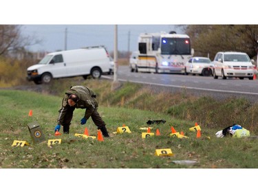 Sûreté du Québec police investigators go over the scene of a police shooting in Saint-Jean-sur-Richelieu near Montreal on Monday October 20, 2014.  An evidence bag covers a knife the suspect is alleged to have been holding when he was shot dead by police.  A police officer identified the man as Martin Couture Rouleau, 25, a local resident.