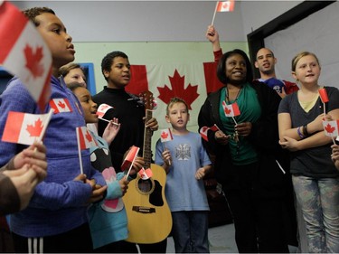 Young people and adults sing O Canada during a vigil.