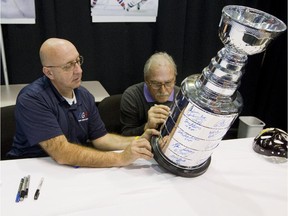 MONTREAL, QUE.: OCTOBER 25, 2014 -- Former Montreal Canadiens goaltender Rogie Vachon, right, signs a Stanley Cup replica as Robert Girard holds it, at a sports collectibles show at Centre Pierre Charbonneau in Montreal, Saturday, October 25, 2014.  (Phil Carpenter / MONTREAL GAZETTE)  ORG XMIT: 1027 SPT-VACHON