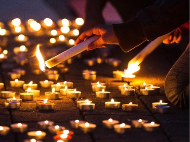 A girl lights candles to spell out Canada during a vigil organized by Arab-Canadian women to honour slain soldiers Corporal Nathan Cirillo and Warrant Officer Patrice Vincent at Place des Arts in Montreal on Tuesday, Oct. 28, 2014.