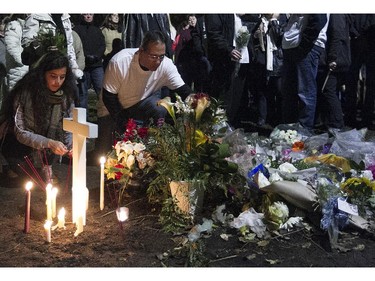 John Gandolfo, centre, father of Jenique, kneels next to flower memorial for Jenique Dalcourt on Tuesday October 28, 2014. The 23-year-old woman was killed last week in Longueuil while riding her bike.