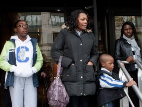 Casey Fuh-Cham, 12, left to right, her mother Yvette Fuh-Cham and little brother Andy Fuh-Cham, four, wait with supporters on the step of the federal courthouse in Montreal on Tuesday, Oct. 7, 2014. The Fuh-Cham family fear deportation back to Cameroon and were attending a hearing.