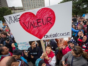 A boy holds a poster as protesters take part in a demonstration opposing the proposed Charter of Quebec Values by the Parti Quebecois government led by Pauline Marois in downtown Montreal on Saturday, September 14, 2013.