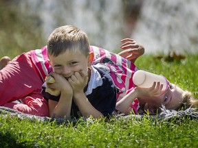 5 year old Noah Parsons waits patiently to finish his sandwich as his 6 year old sister Maartje rolls around on top of him during a family picnic in Pointe Claire in September 2014.