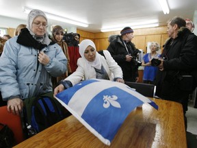 Montrealer Dr Najat Boughaba lays down a Quebec flag at her table on her arrival with several other Muslim women at the  Age d'Or Club in Hérouxville, Qc Sunday, February 10, 2007. The women came to the town to discuss town councillor André Drouin's rules for would-be immigrants and to bring residents gifts. The town council had passed a list of societal norms for would-be immigrants  - particularly Muslims -  saying, for instance, a man cannot stone a woman to death or burn her with acid and faces are not to be covered except at Halloween.
