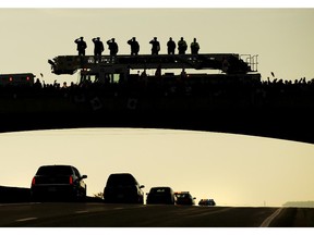 Supporters pay tribute as the Body of Cpl. Nathan Cirillo is transported from Ottawa to Hamilton, along the Highway of Heroes in Port Hope, Ont., on Friday, October 24, 2014. The 24-year-old reservist was gunned down as he stood ceremonial guard at the National War Memorial in Ottawa on Wednesday.