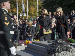 People pay their respects as sentries guard the Tomb of the Unknown Soldier at the National War Memorial in Ottawa on Friday, Oct. 24, 2014. The sentries returned to their posts two days after Cpl. Nathan Cirillo, 24, a reservist from Hamilton, Ont., was killed by a gunman while guarding the tomb.