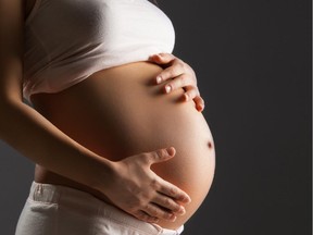 A pregnant woman caresses her belly.