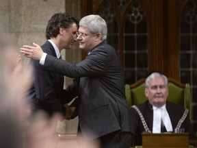 Prime Minister Stephen Harper hugs the leader of the Liberal Party of Canada Justin Trudeau, as Sergeant-at-Arms Kevin Vickers, right, looks on in the House of Commons on Thursday Oct. 23, 2014 in Ottawa. The House of Commons is back in action, kicked off by an exhilarating show of support for Vickers, who was among those who opened fire on Michael Zehaf Bibeau, who stormed Parliament Hill on Wednesday.
