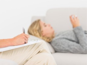 A therapist takes notes while a client talks.