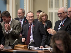 Quebec Treasury Board president Martin Coiteux, centre, is applauded after he tabled legislation Thursday, Oct. 9, 2014, at the legislature in Quebec City.