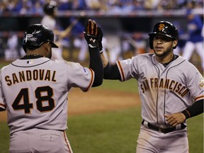 San Francisco Giants' Gregor Blanco is congratulated by teammate Pablo Sandoval (48) after scoring on an RBI triple by San Francisco Giants second baseman Joe Panik during the seventh inning of Game 1 of baseball's World Series Tuesday, Oct. 21, 2014, in Kansas City, Mo.
