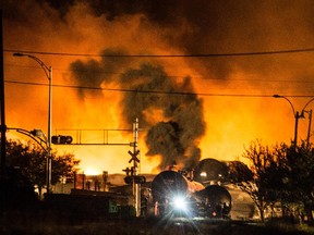 Smoke and fire rises over train cars as firefighters inspect the area after a train carrying crude oil derailed and exploded in the town of Lac-Mégantic in July 2013.