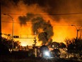 Smoke and fire rises over train cars as firefighters inspect the area after a train carrying crude oil derailed and exploded in the town of Lac-Mégantic in July 2013.