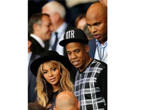 Jay Z and his wife Beyonce stand up at half time in the Champions League soccer match between PSG and Barcelona, at the Parc des Princes stadium, in Paris, Tuesday, Sept. 30, 2014. The showbiz power couple are scouting out potential homes while in Paris on holiday.